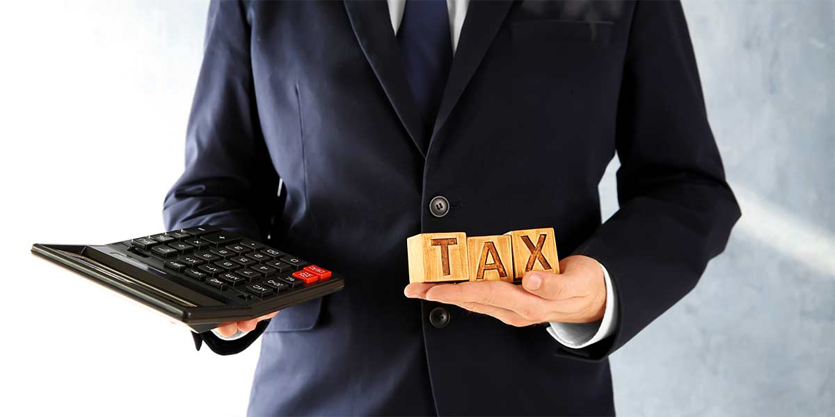 What Is a 1031 Exchange? We see here a professional holding a big calculator and cudes that read TAX
